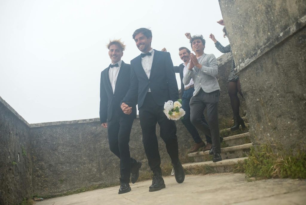Happy couple and friends celebrating a wedding outdoors in Portugal, showcasing love and togetherness.
